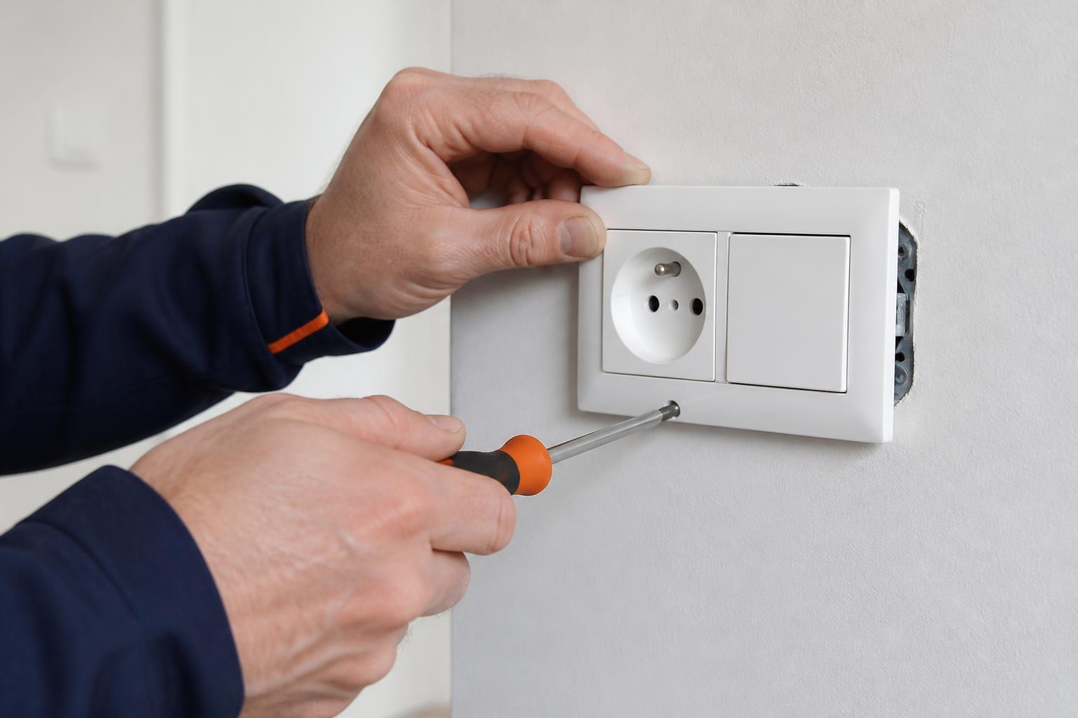 Elektricien plaatst een stopcontact en schakelaar op een afgewerkte muur